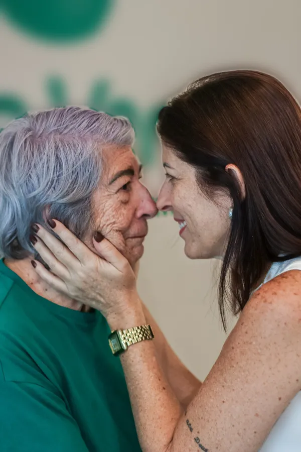 Suzana tem o rosto acolhido pelas mãos de uma mulher da família